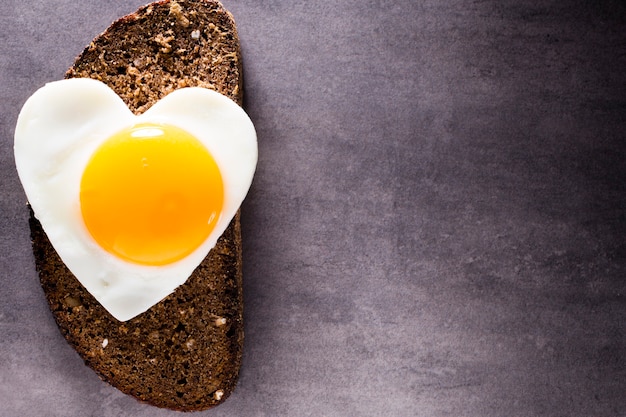 Fried egg on heart-shaped slice of bread.