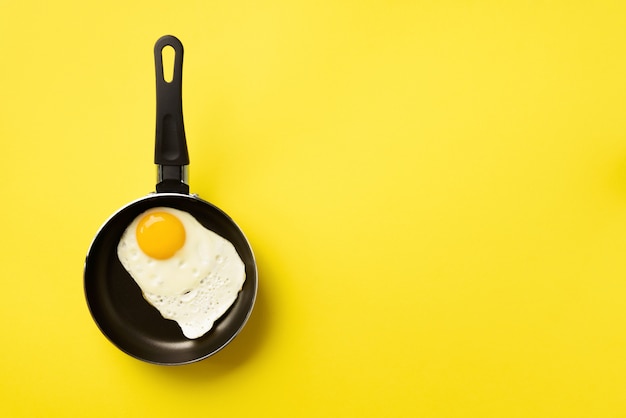 fried egg on pan over yellow background