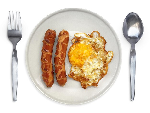 Fried egg on a plate with spoon and fork sausage on a white background