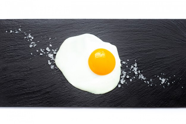 Fried egg on slate plate with salt. Cooking and food concept.