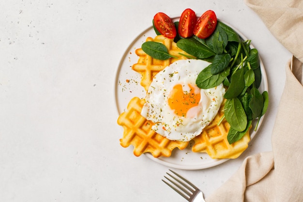 Fried egg spinach waffles on white background