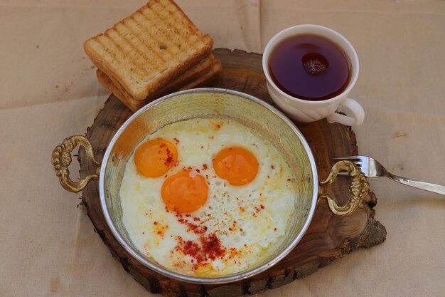 fried egg, tea and toast on wooden background