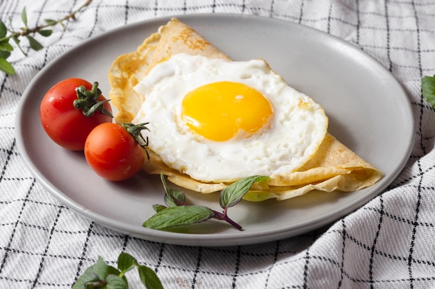 Foto uovo fritto con crespelle e pomodorini