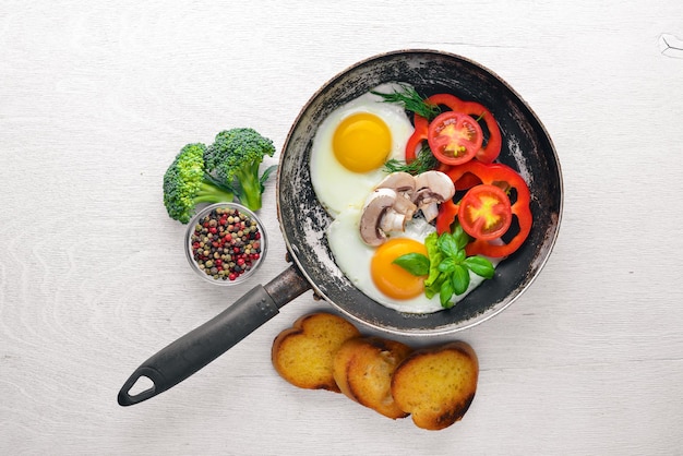 Fried egg with herbs, toast bread and vegetables in a frying pan. Top view. Free space.