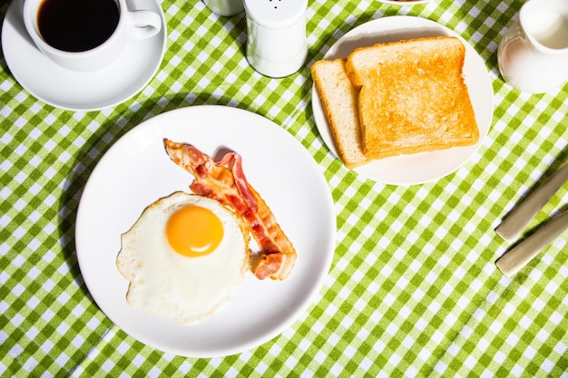 Photo fried egg with roasted bacon black coffee toasts retro american breakfast hard shadow top view
