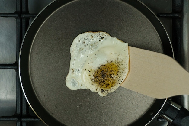 Fried egg with spices in a frying pan and a spatula