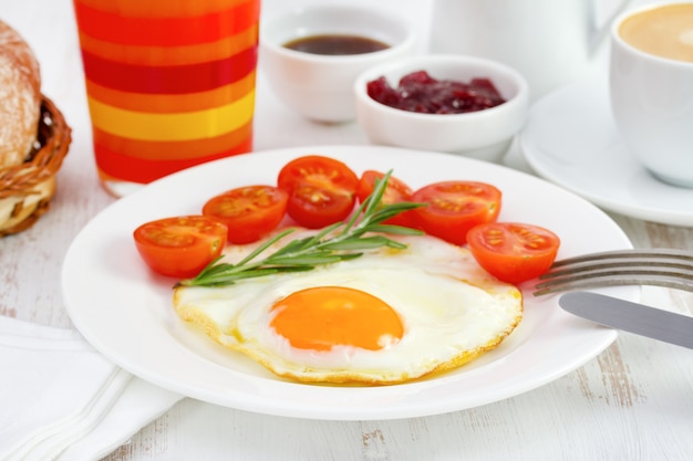 Жареное яйцо с помидорами и стаканом апельсинового сока