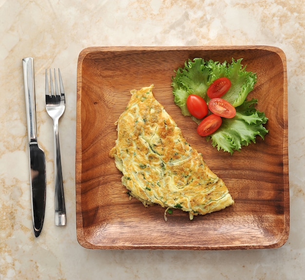 Fried eggs from quail eggs with spinach in a wooden plate with lettuce and tomatoes