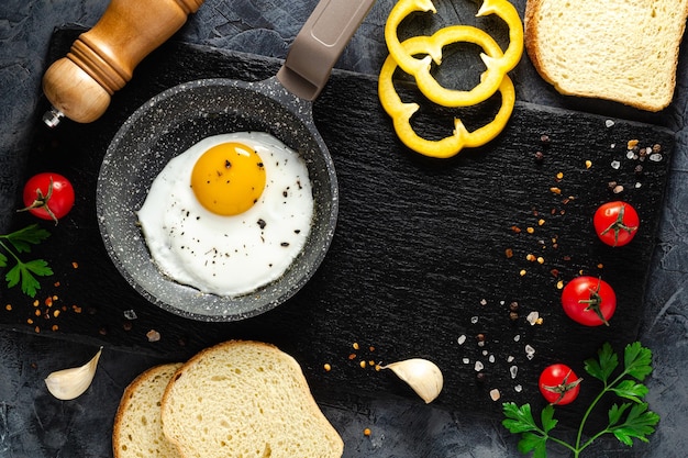 Fried eggs in a frying pan with fresh vegetables and spices. Concept for menu and advertising.