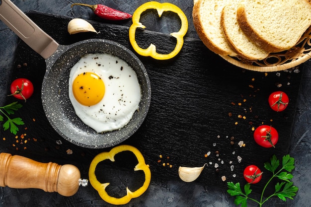 Fried eggs in a frying pan with fresh vegetables and spices. Concept for menu and advertising.