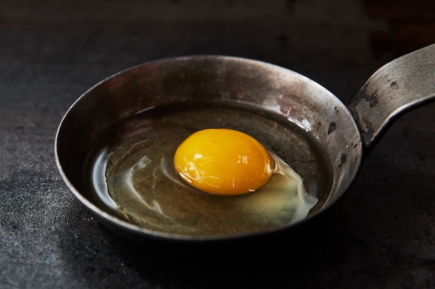 Fried eggs in oil in a pan on a black surface