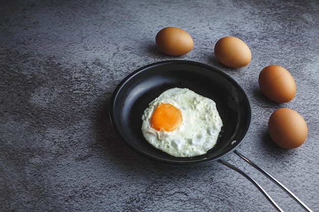 Fried eggs in a pan and fresh eggs on the table