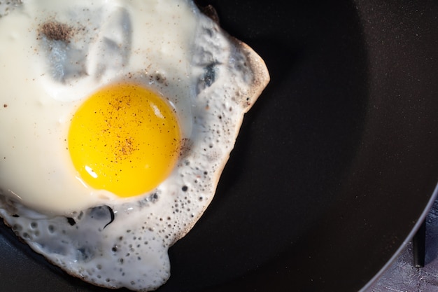 Fried eggs in a pan isolated on a black  close-up. View from above.