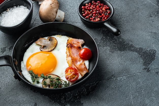 Fried eggs with bacon and vegetables set in cast iron frying pan