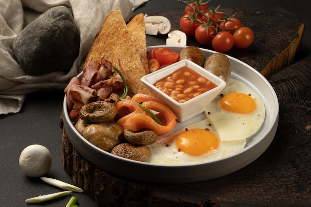 Яичница с фасолью в томатном соусе, жареные грибы, бекон, лосось, куриные колбаски, помидоры черри и тосты. Сытный завтрак