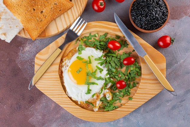 Fried eggs with cherry tomatoes and bread on marble table.