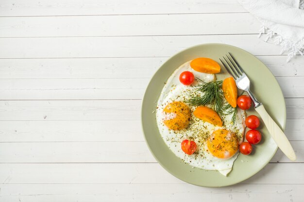 Uova fritte con i pomodori ciliegia su un piatto