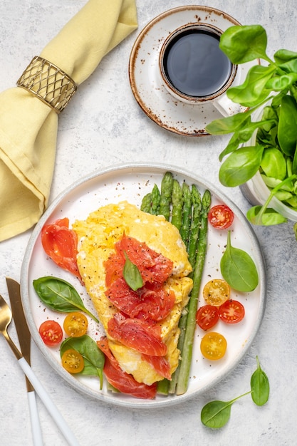 Fried eggs with green asparagus and salmon, cherry tomatoes and fresh spinach. 