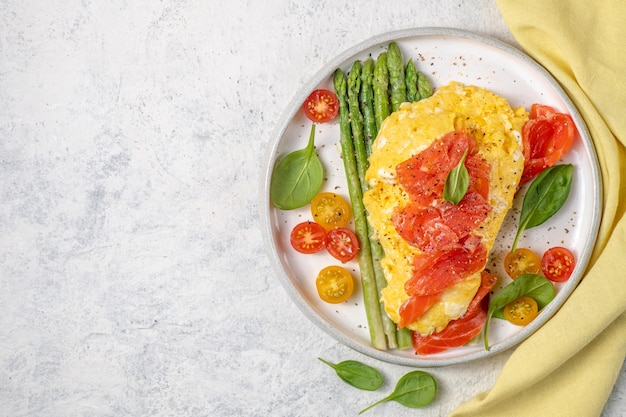 Fried eggs with green asparagus and salmon, cherry tomatoes and fresh spinach. 