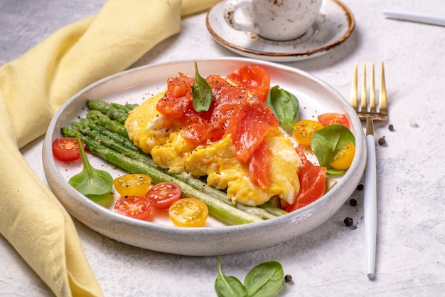 Fried eggs with green asparagus and salmon, cherry tomatoes and fresh spinach. 