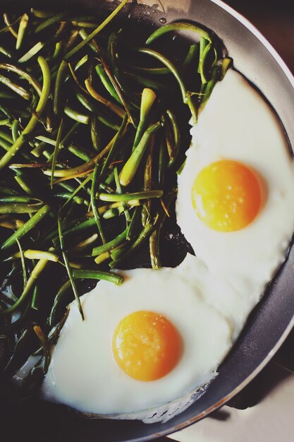 Fried eggs with green beans on the pan close up