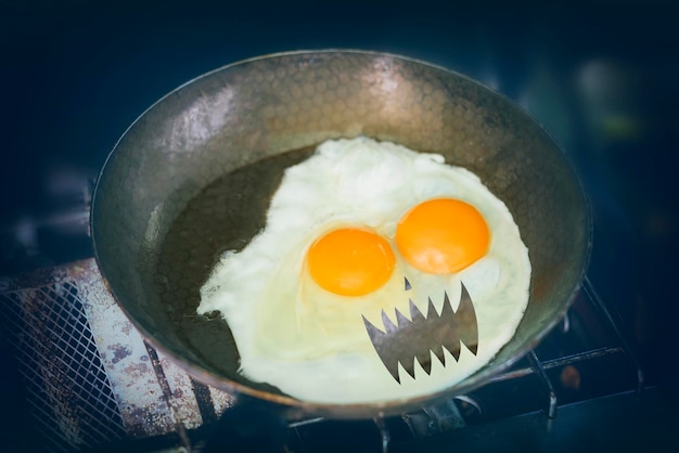 Fried eggs with Halloween face in a pan on a gas stove