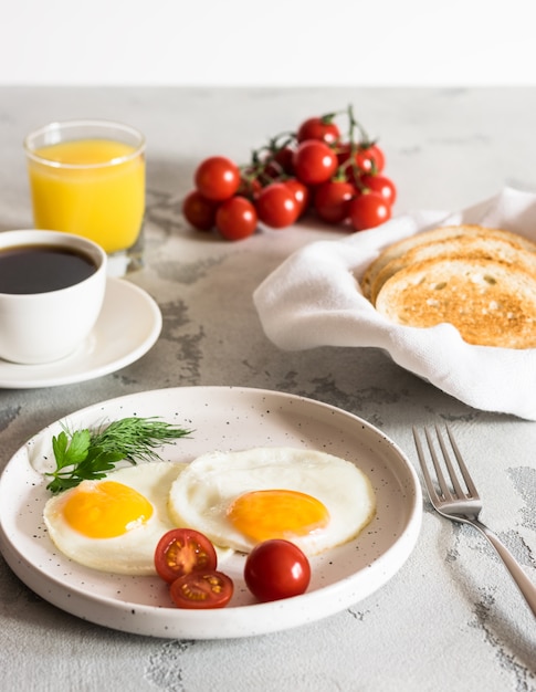 Foto uova fritte con erbe aromatiche, pomodori rossi, pane tostato, caffè e succo fresco