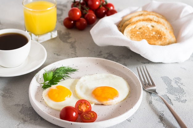 Uova fritte con erbe aromatiche, pomodori rossi, pane tostato, caffè e succo fresco