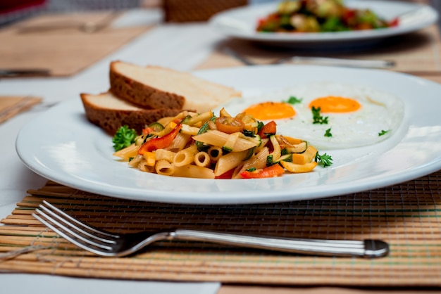 Fried eggs with pasta on the white plate