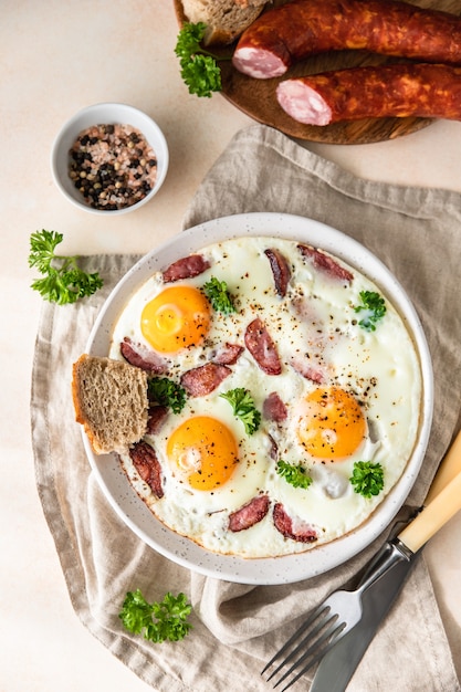 Fried eggs with sausage and parsley on a ceramic plate served with bread Classic breakfast