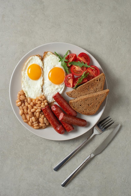 Fried eggs with sausages and beans in a plate on a gray background English breakfastxA