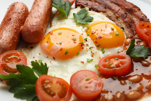 Fried eggs with sausages, vegetables and spices, close up