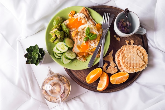 Fried eggs with toasts and tea in bed