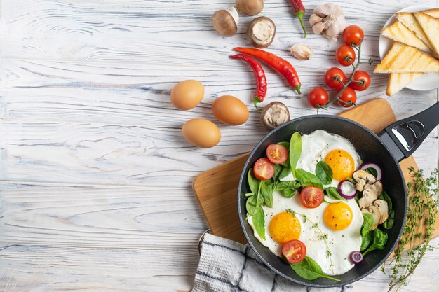 Fried eggs with tomatoes, mushrooms and spinach leaves