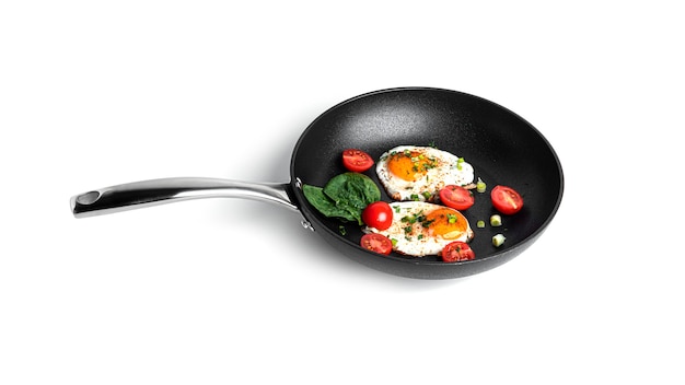 Fried eggs with vegetables on the pan isolated on a white background. Beautiful breakfast. High quality photo