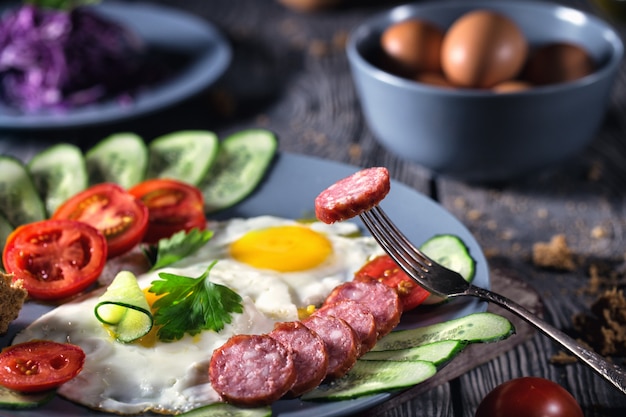 Fried eggs with vegetables and sausage