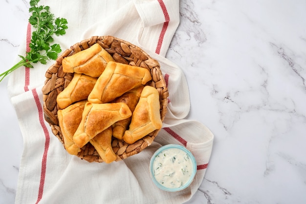 Fried empanadas with cilantro, meat, egg, tomato and chili sauce on white background. Latin American and Chilean independence day concept.