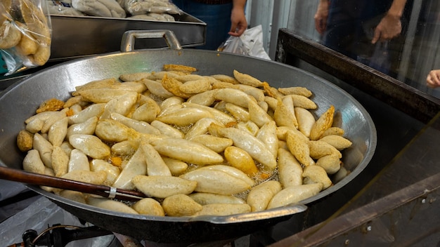 Photo fried fish balls with rugby shape in a pan with boiling oil with traditional asian street food in the hot oil on market at thailand