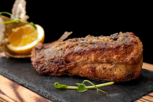 Fried fish on black slate on a wooden board. Flounder