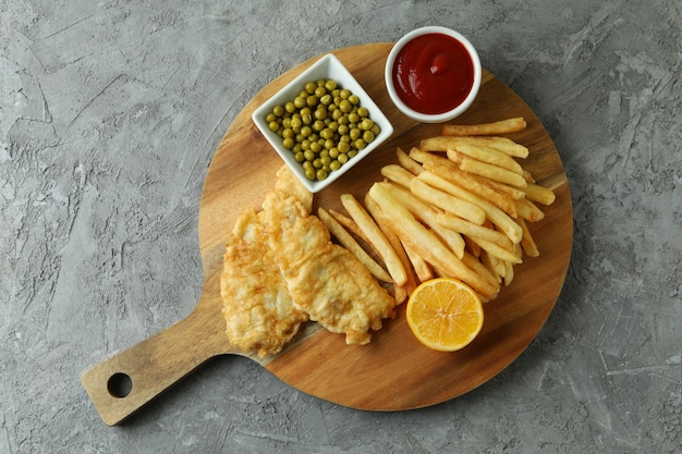 Pesce fritto e patatine fritte su sfondo grigio con texture