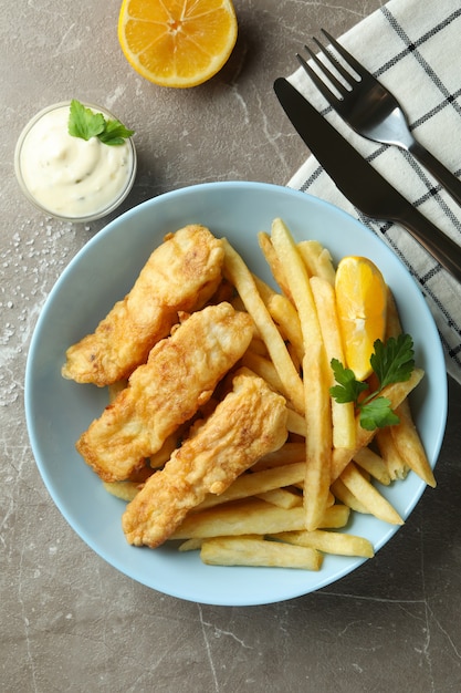 Photo fried fish and chips on gray textured table