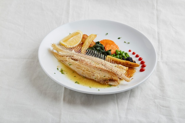 Fried fish fillet and vegetables on a white plate