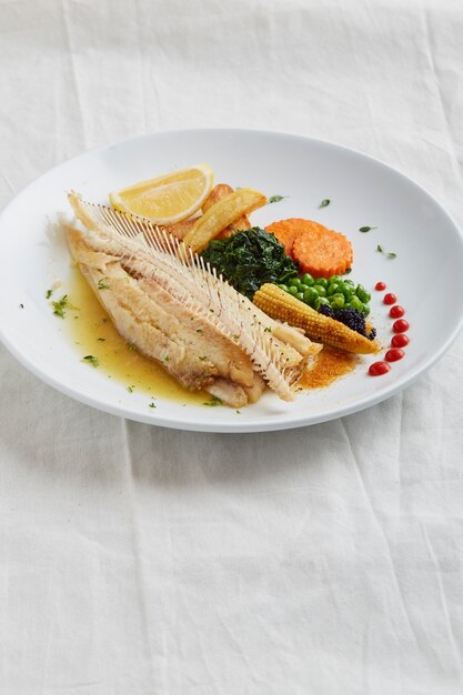 Fried fish fillet and vegetables on a white plate