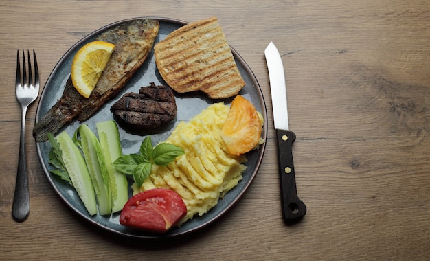 写真 魚のフライ、ミートステーキ、野菜の盛り合わせ