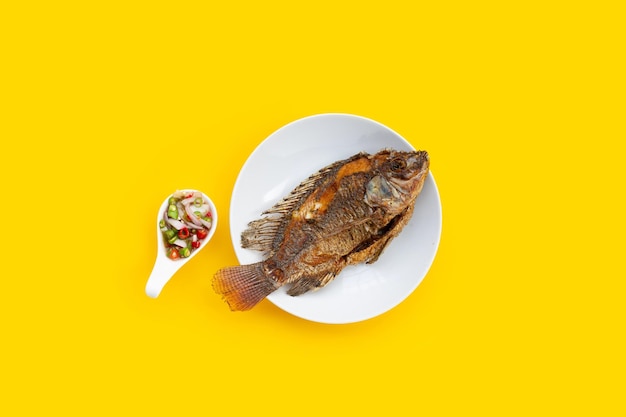 Fried fish in white plate on yellow background