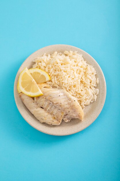 Fried fish with boiled white rice on white dish