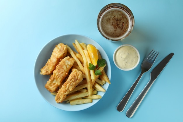 fried fish with chips and beer isolated on blue