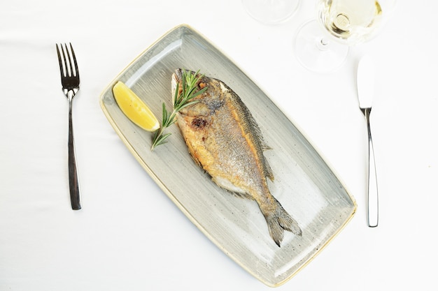 Fried fish with lemon and rosemary on a plate