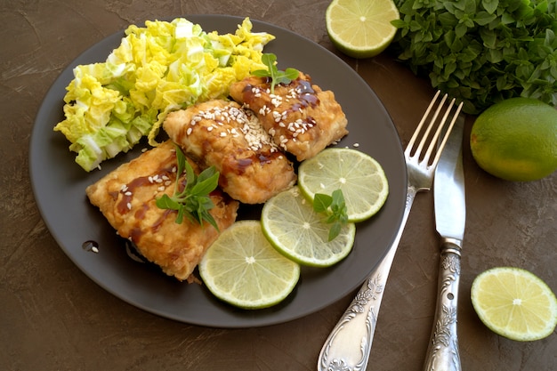 Foto pesce fritto con insalata su un piatto grigio.