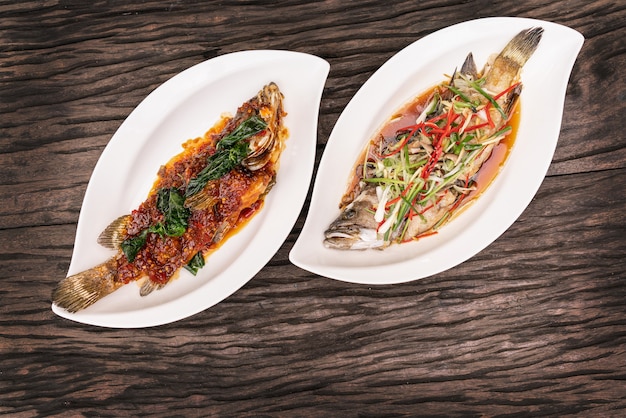 Fried fish with spicy salad in plate on wooden table with copy space